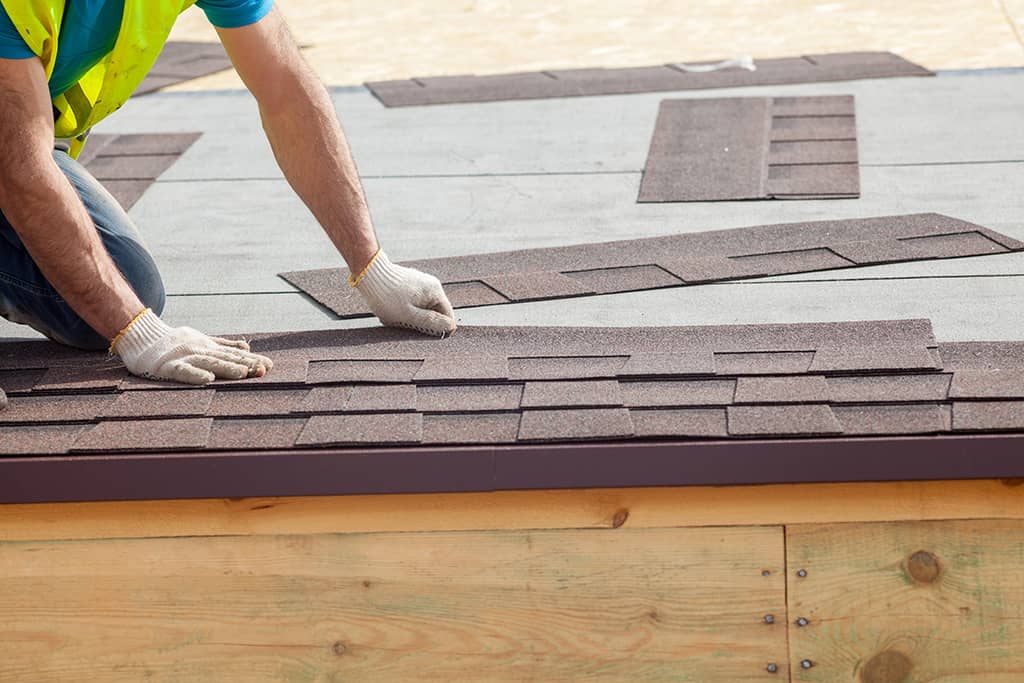 Roofer builder worker installing roof shingles